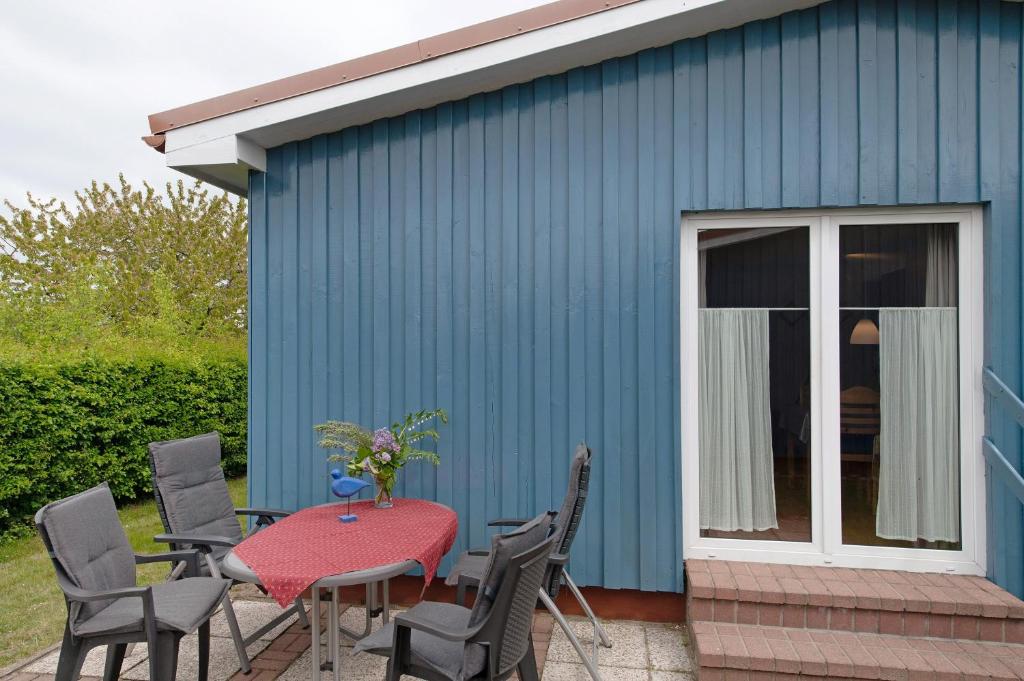 a patio with a table and chairs and a blue building at Möve Aba Bungalow 67 in Rerik