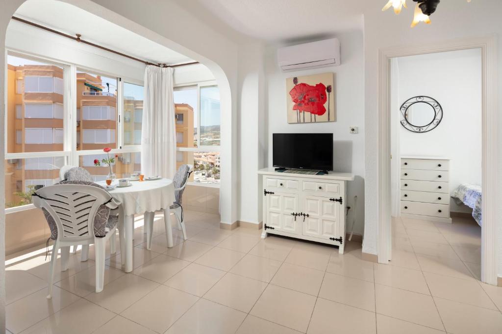 ein weißes Esszimmer mit einem Tisch und einem Fernseher in der Unterkunft Bloque 78 in Torrox