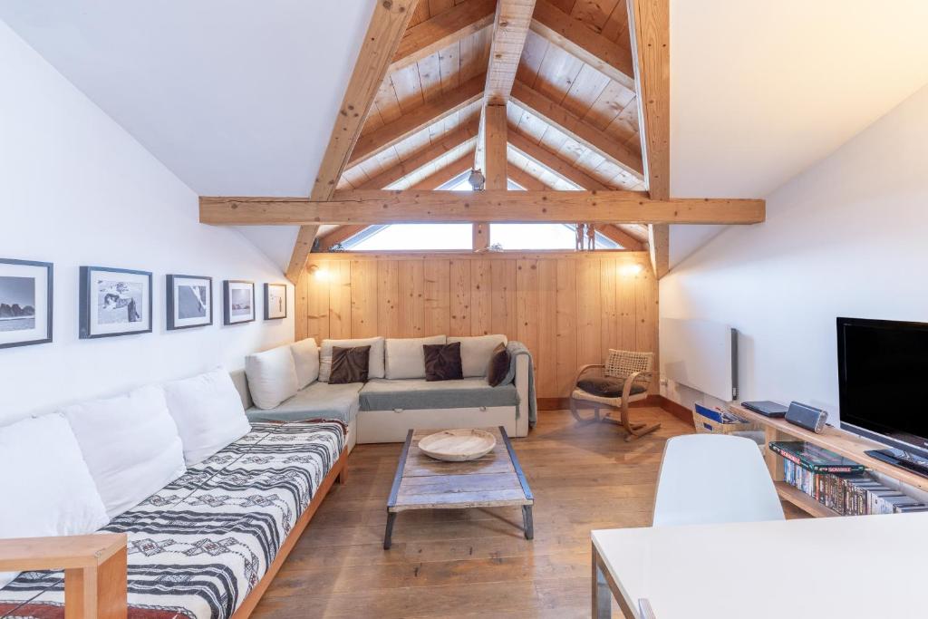 a living room with a couch and a tv at Appartement style loft Chamonix in Les Houches