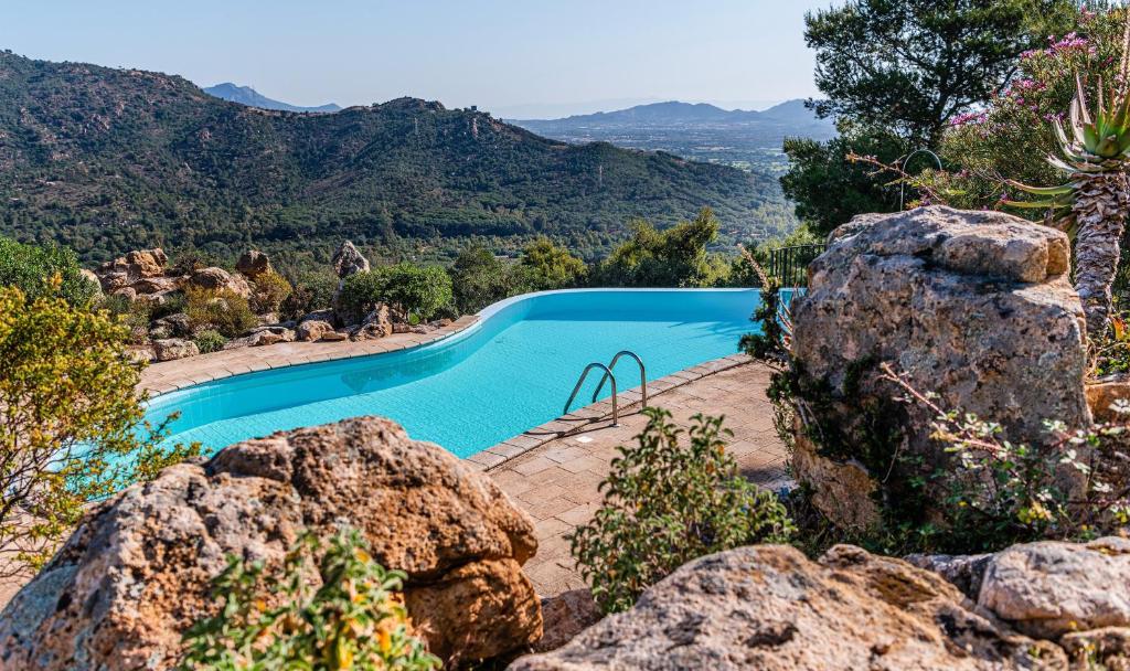 a swimming pool with mountains in the background at Villa Aquila Giardino in Is Molas 
