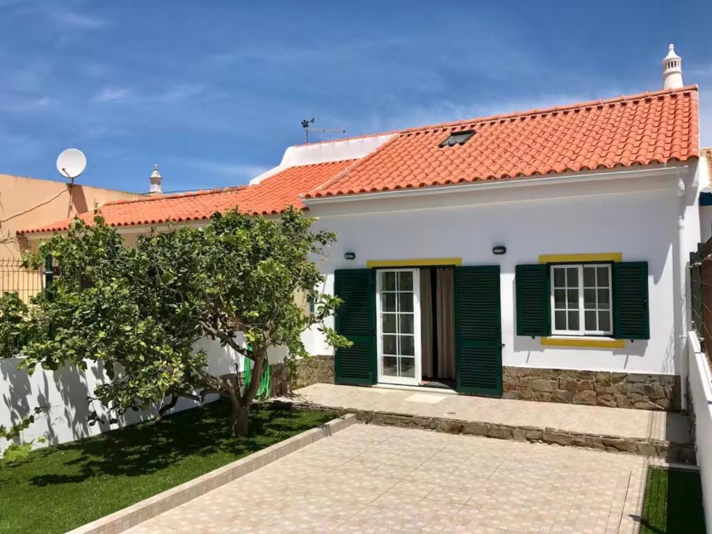 a white house with a red roof and green shutters at Casa Sagres in Vila do Bispo