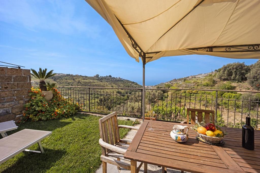 a wooden table with a bowl of fruit and a umbrella at Pelagos in Pompeiana