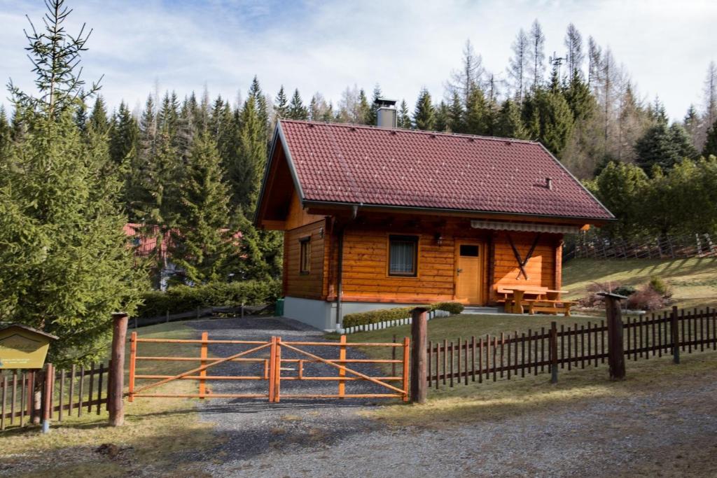 a wooden cabin with a fence and trees at Ferienhaus Klippitzblick in Klippitztorl