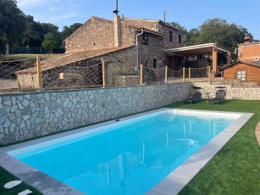 a swimming pool in front of a stone house at Masia Can Vilar in Maçanet de la Selva
