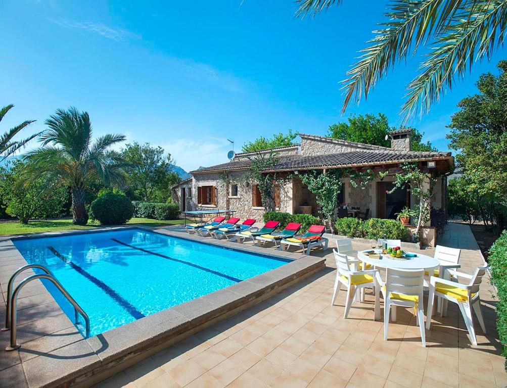 a pool with chairs and a table and a house at Villa Tancotes in Pollença