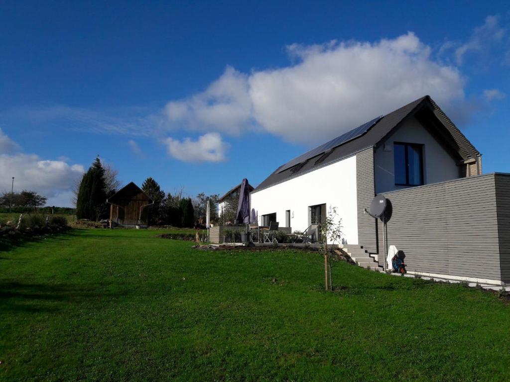 a white building with a gambrel roof on a grass field at Charmingsuite in Bad Teinach-Zavelstein
