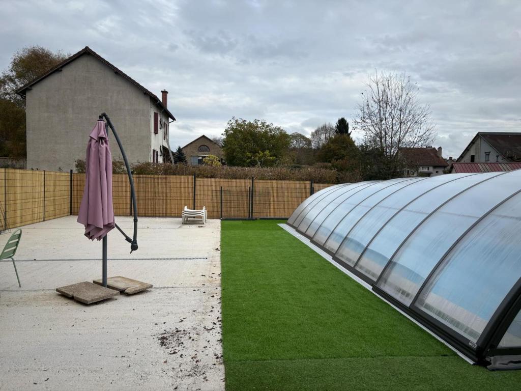 a glass greenhouse with an umbrella in a yard at Maison de vacances avec piscine in Messeix