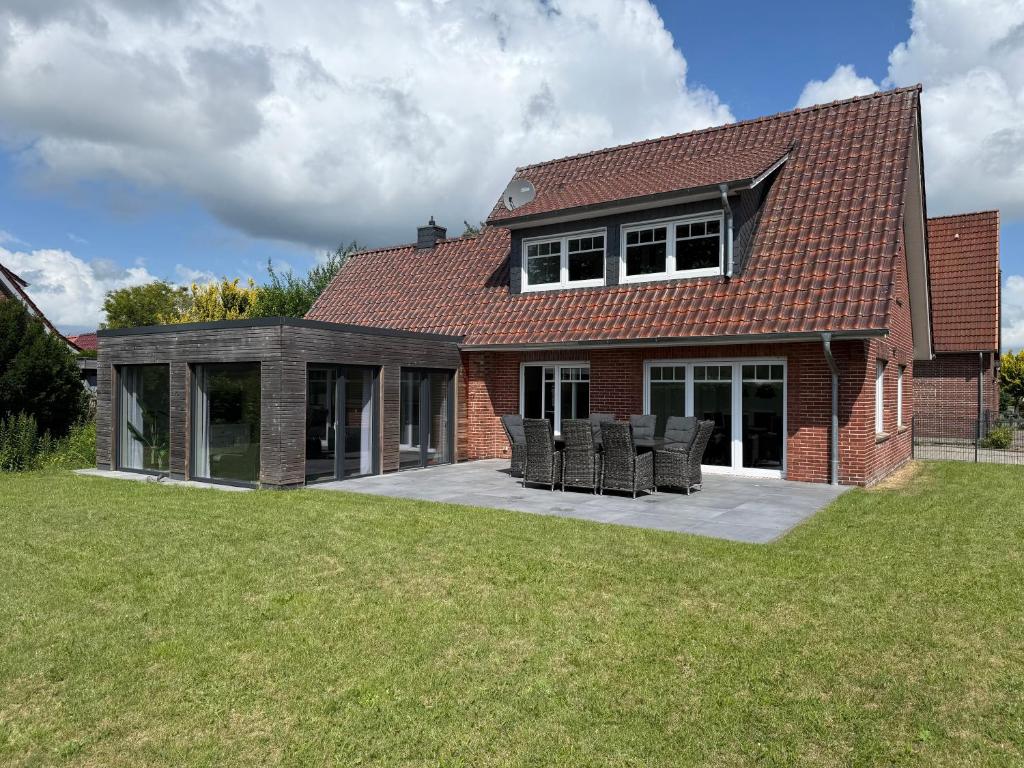 a red brick house with chairs on a patio at Ferienhaus Neeborg in Zetel