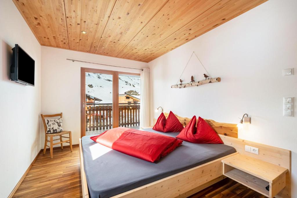 a bedroom with a bed with red pillows at Seppnerhof Ferienwohnung Enzian in Moso