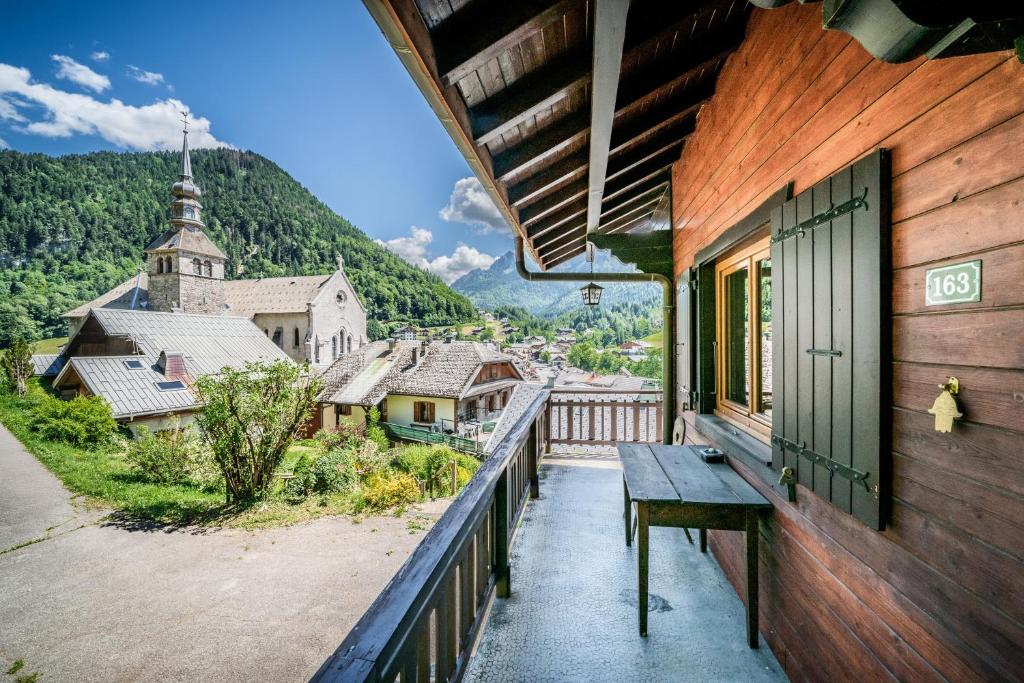 a balcony of a house with a bench and a church at Chalet Chez Juju in Abondance
