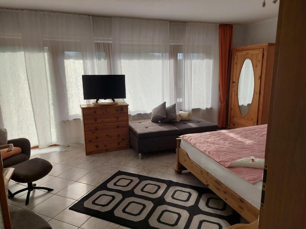 a bedroom with a bed and a couch and a chair at Ferienwohnung-Pension Osterwiese in Weilburg