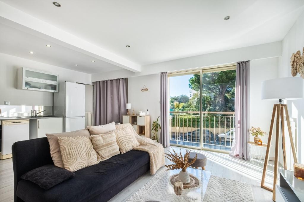 a living room with a black couch and a large window at T2 Cyril Besset in Cagnes-sur-Mer