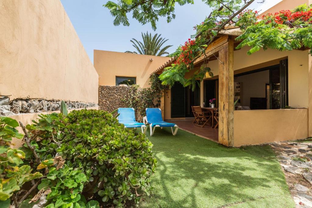 a yard with two chairs and a house at Villa Orquidea in Tamaragua