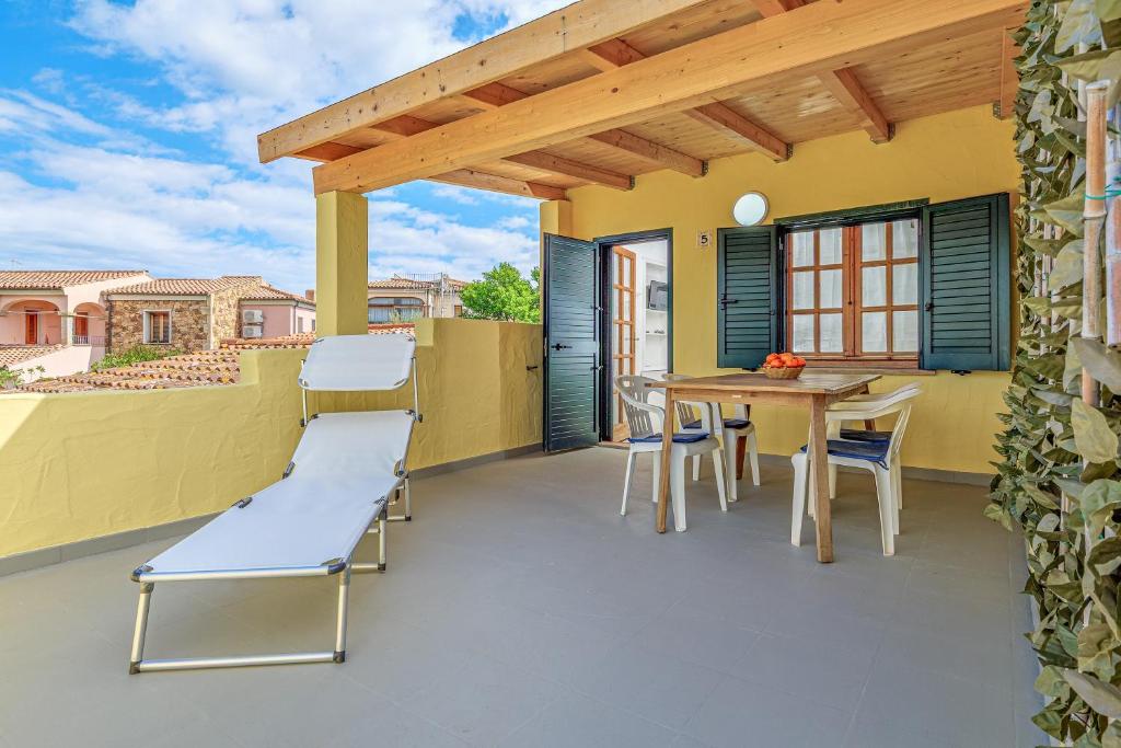 a patio with a wooden pergola and a table and chairs at I giardini di Cala D'ambra in San Teodoro