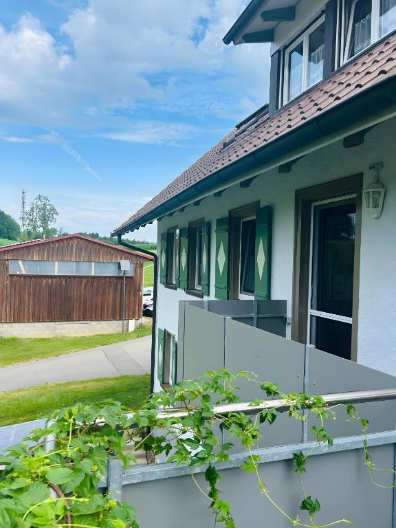 a house with a porch with a fence at Ferienwohnung Bauernpfad in Kressbronn am Bodensee