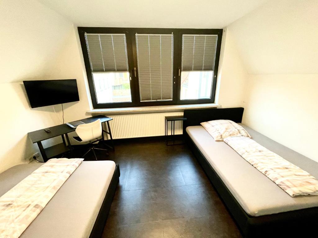 dwa łóżka w pokoju z biurkiem i oknem w obiekcie Ferienwohnung Khorsandi Eins w mieście Coburg