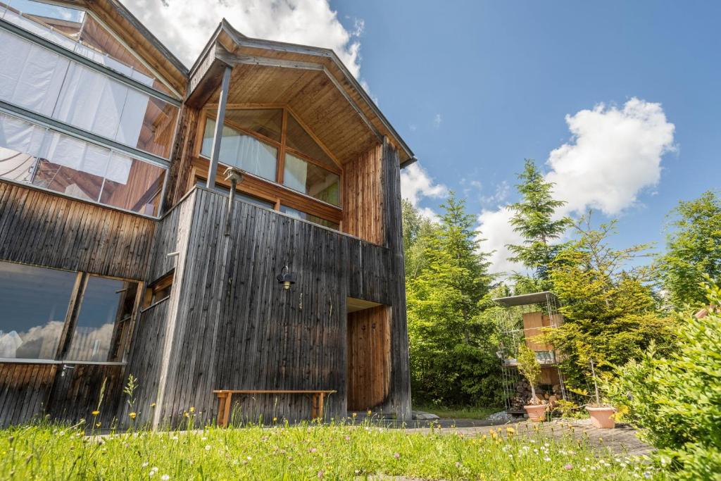 a wooden house with a lot of windows at Haus der Sinne Bregenzerwald in Tannen
