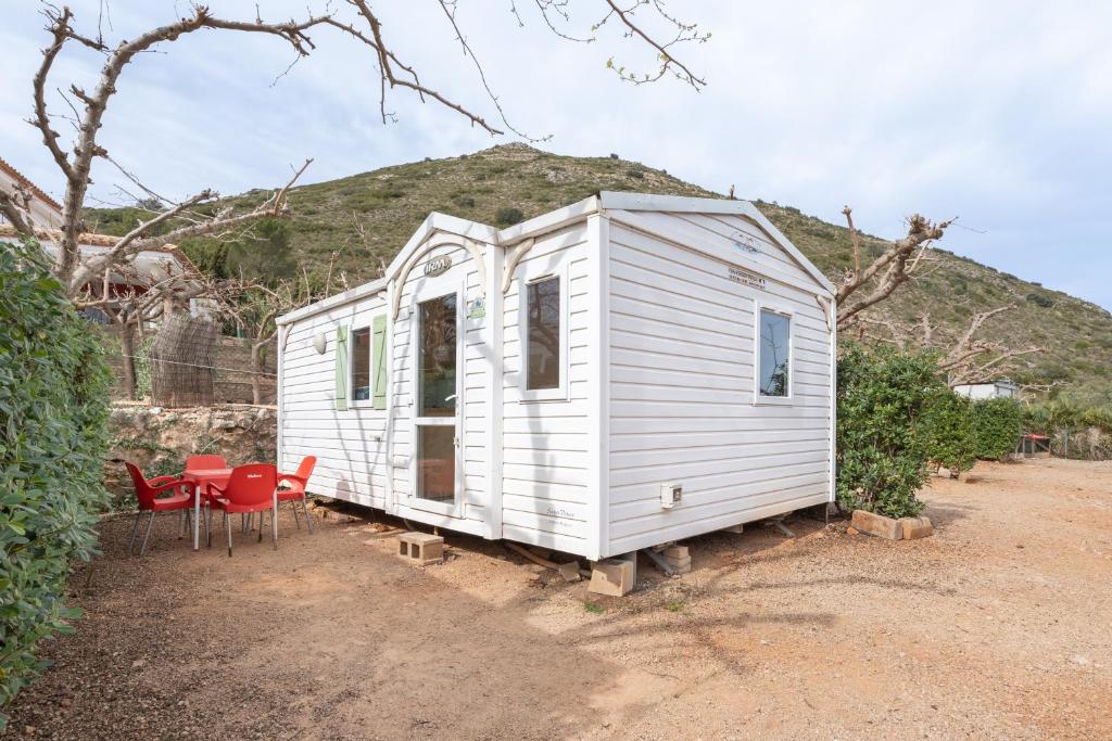 a white tiny house with a table and chairs at Falaguera Bungalow 5 in Bárig
