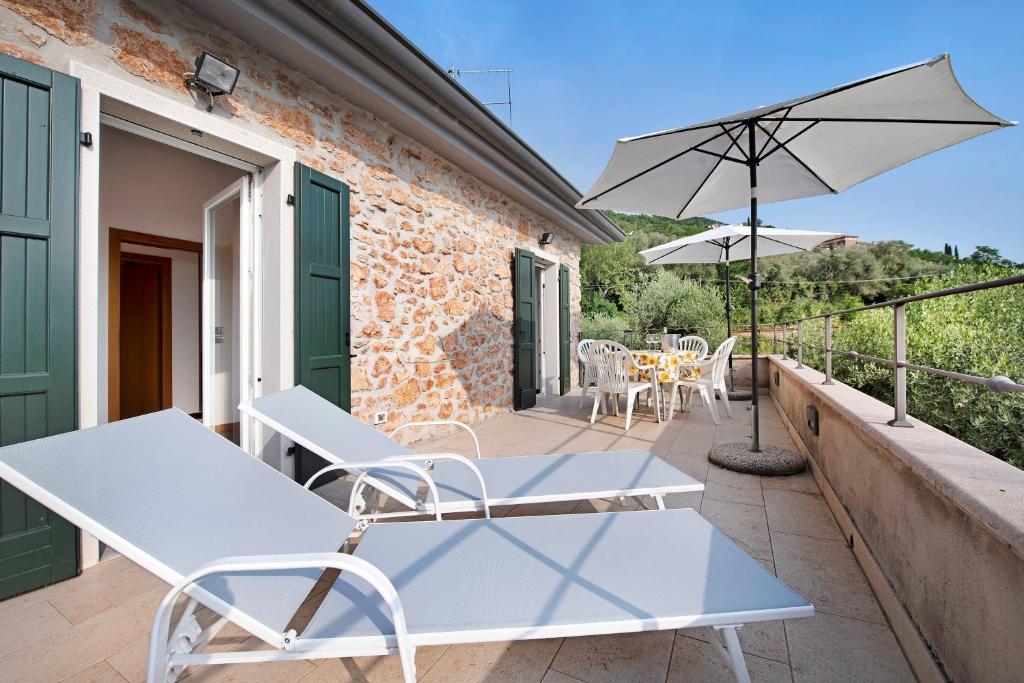 a patio with a table and chairs and an umbrella at Rustico alle Fornare in Torri del Benaco