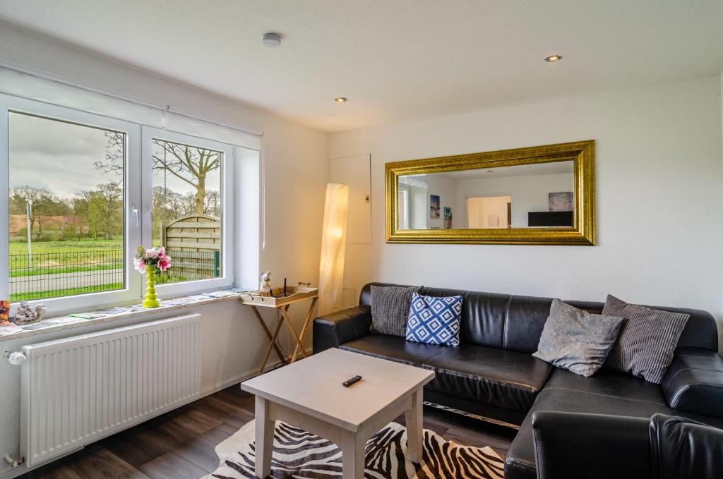 a living room with a black leather couch and a window at Krummes Häusschen an der Nordsee in Großheide
