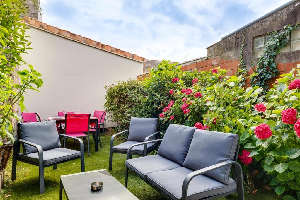 a patio with chairs and tables and flowers at A Bordeaux, Climatisée avec billard in Le Bouscat