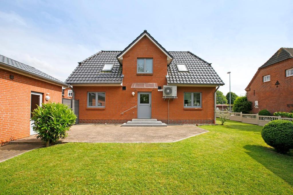 a red brick house with a grass yard at Ferienhaus Siegfried in Niebüll