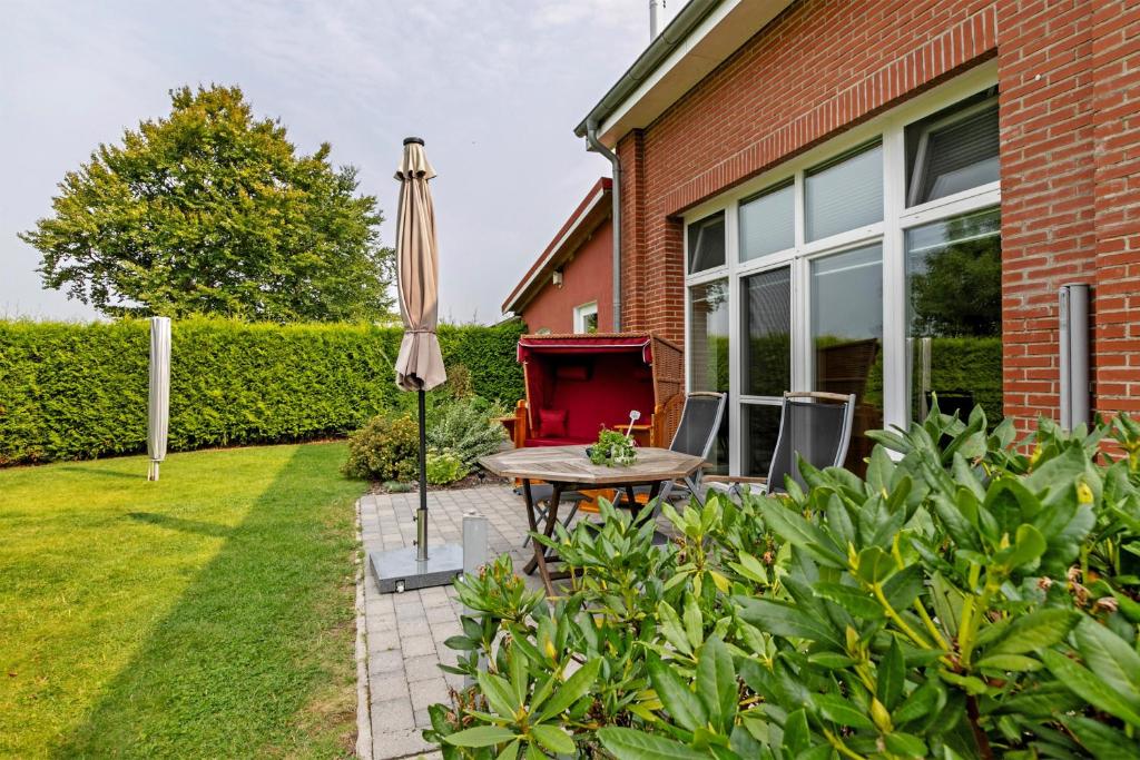a patio with a table and an umbrella in a yard at Ferienwohnung Offenbütteler Moor in Osterrade