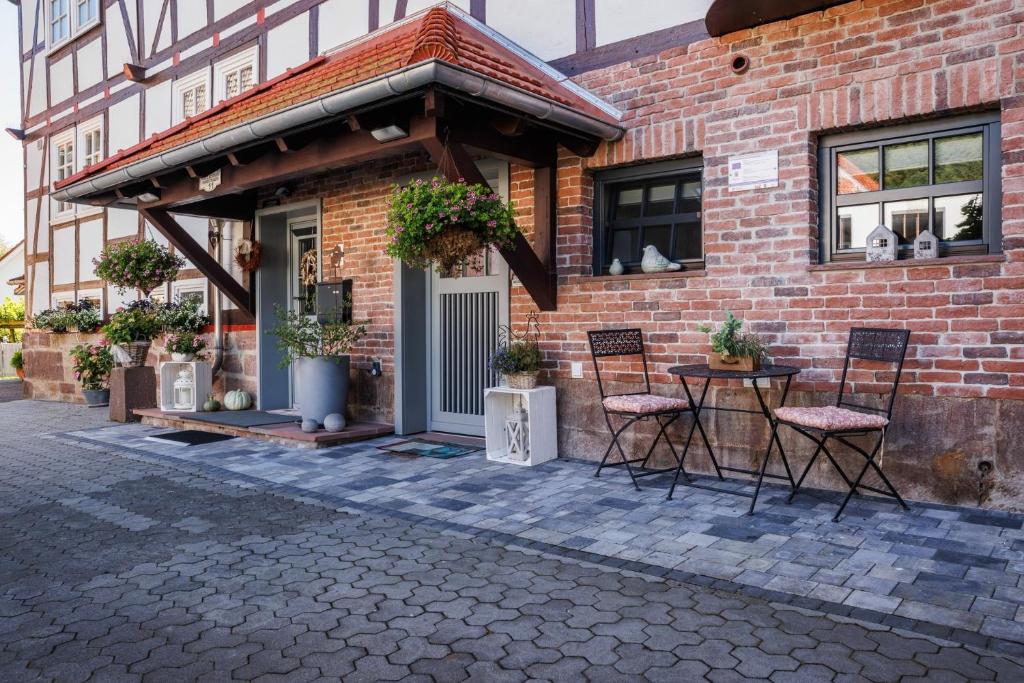 a brick building with chairs and a table in front of it at Ferienwohnung Alter Kuhstall in Neuenstein