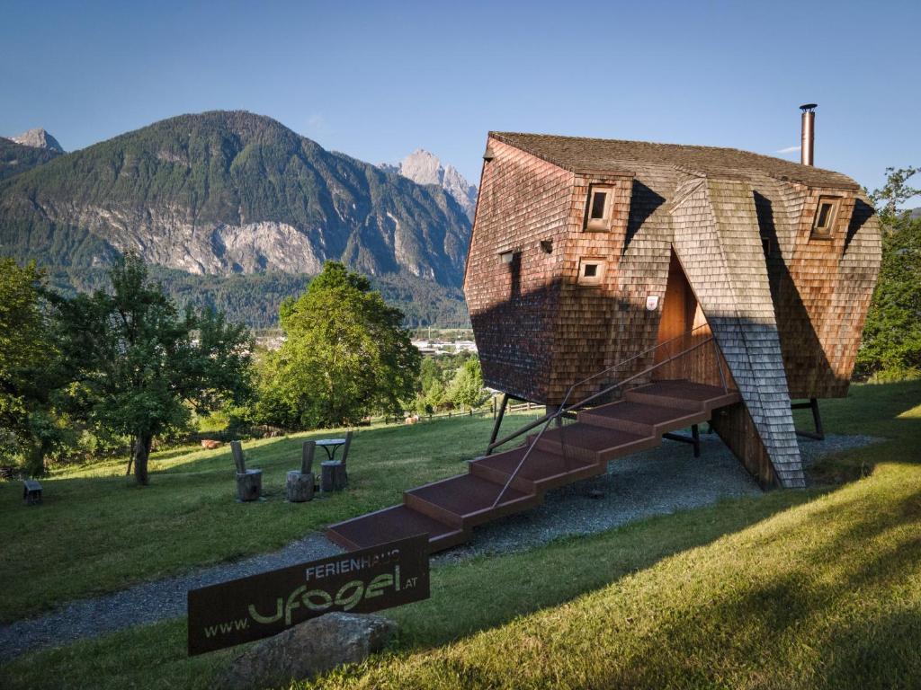 a house with a thatched roof on a field with mountains at Ufogel in Nußdorf