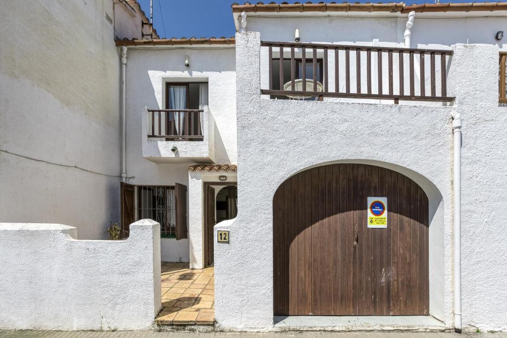 a white building with a wooden door and a balcony at Casa de Riells in L'Escala