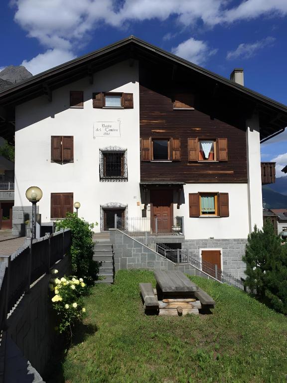 a white house with wooden windows and a yard at Baita Del Canton in Valdidentro