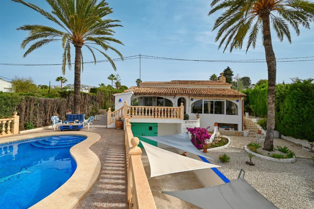 a house with a swimming pool and palm trees at Dulce in Benissa