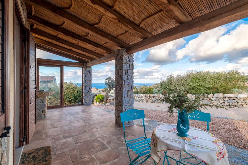a patio with a table and chairs and a view of the ocean at Stazzo Jana in Trinità d'Agultu e Vignola