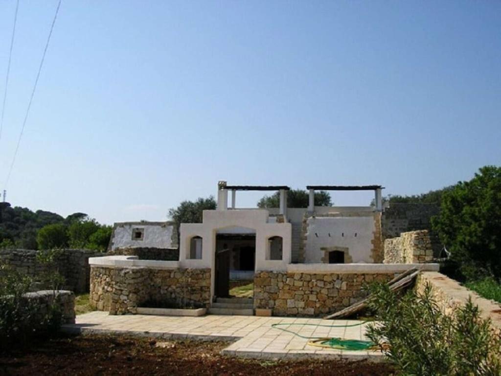 a large white building with a stone wall at Lu Rusciu De Lu Vientu in Castrignano del Capo