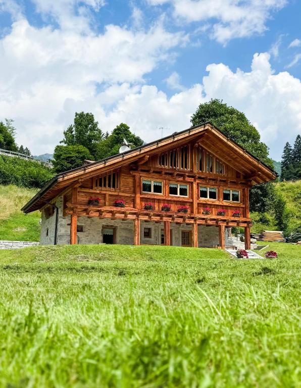 a large wooden house in a field of grass at Maroc Mountain Chalet in Madonna di Campiglio