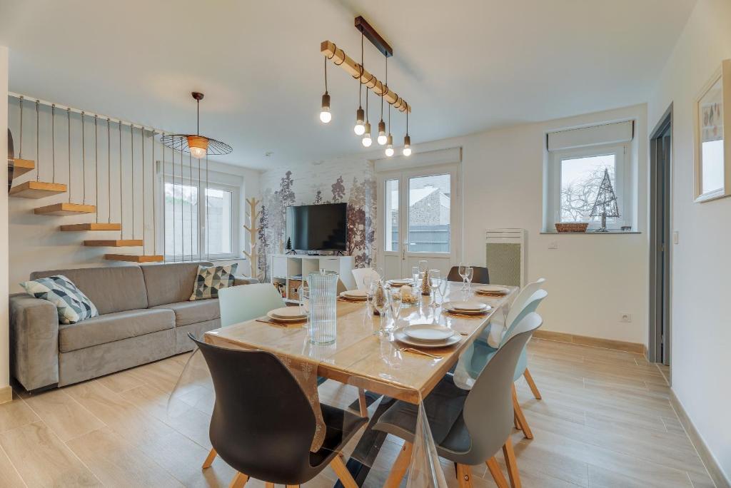 a dining room and living room with a table and chairs at Le Banc des Hermelles in Saint-Benoît-des-Ondes