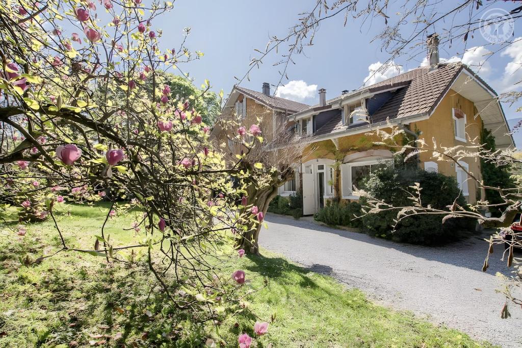 una casa gialla con fiori rosa nel cortile di La Villa a Viviers-du-Lac