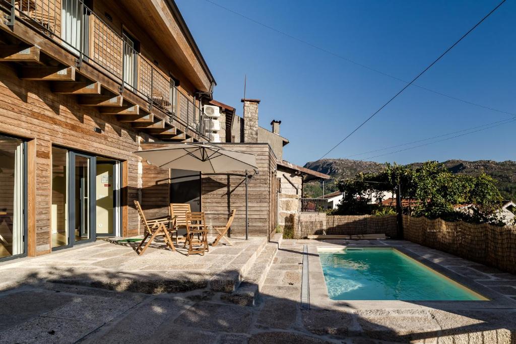 a patio with a table and an umbrella next to a house at Casa Da Avó Custódia in Campo do Gerês