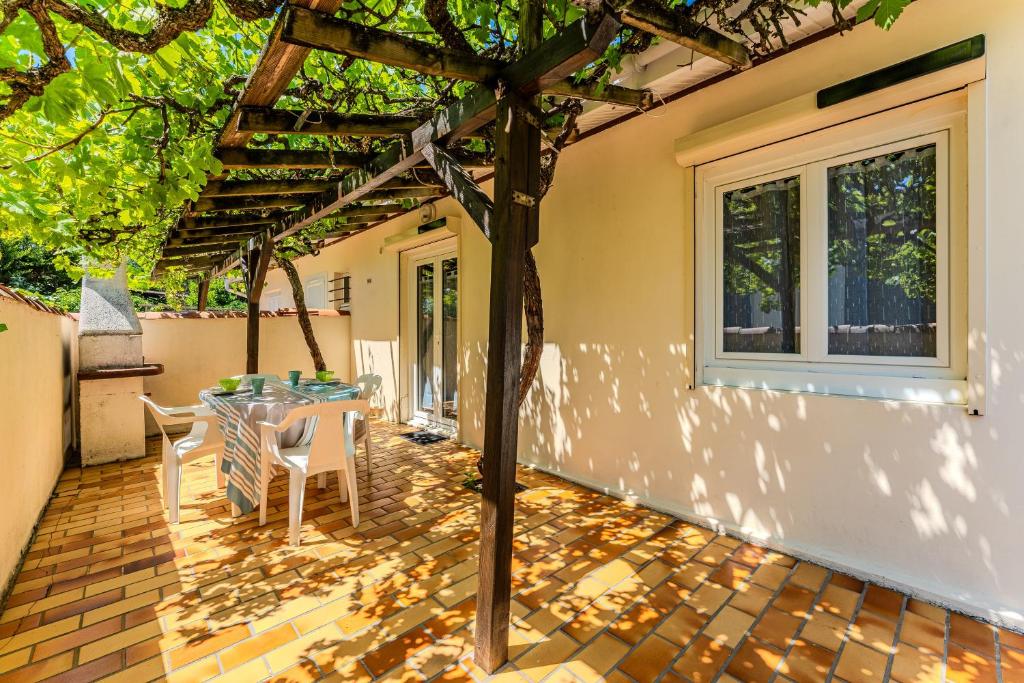 a patio with a table and chairs under a pergola at Maison 3 étoiles, 300m de l’Océan in Biscarrosse