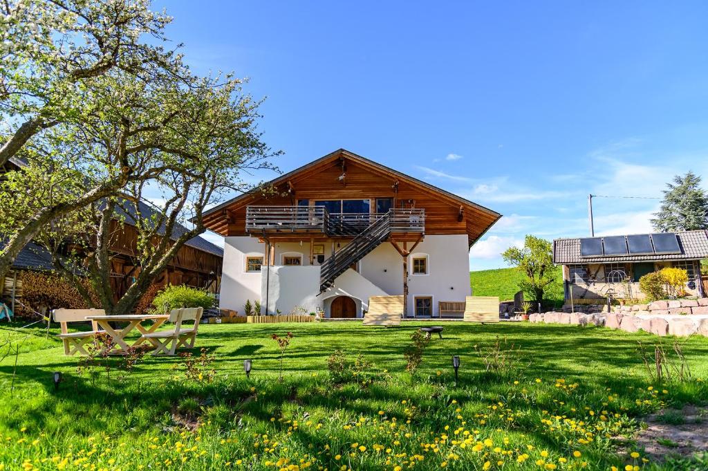 a house with a wooden roof and a grass field at Labe Biohof Oberzonn in Kastelruth