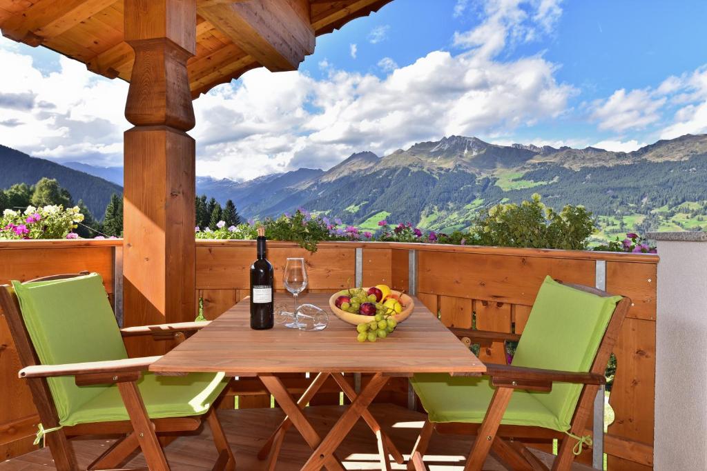 a table on a deck with a bottle of wine and a bowl of fruit at Joselehof App Arnika in Racines
