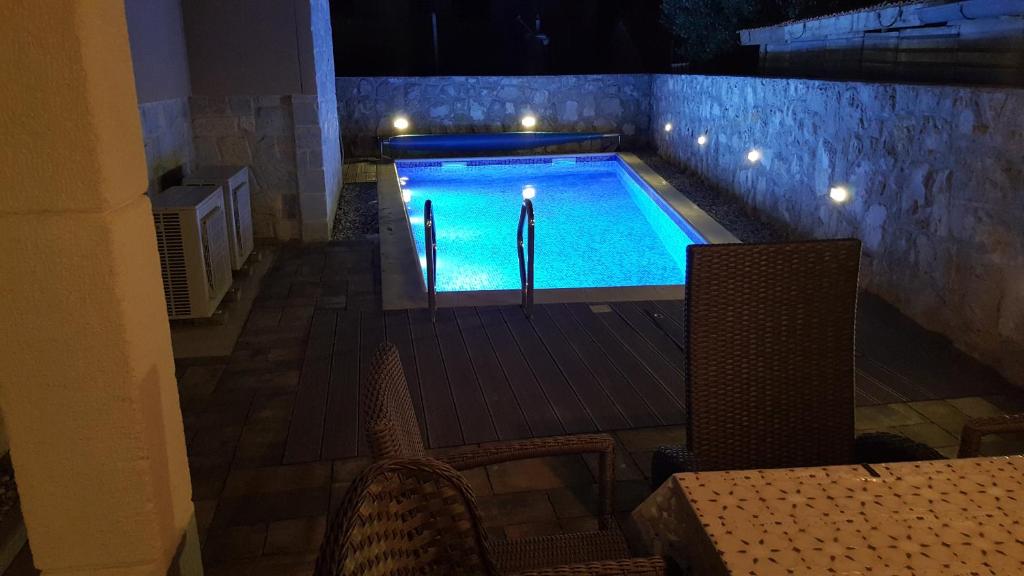 a swimming pool at night with two chairs and a table at Apartments Rustic in Biograd na Moru
