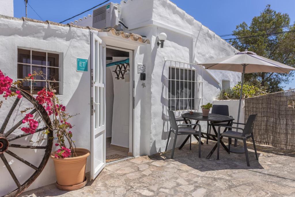 a small white house with a table and an umbrella at Can Vital 1 in Illes Balears