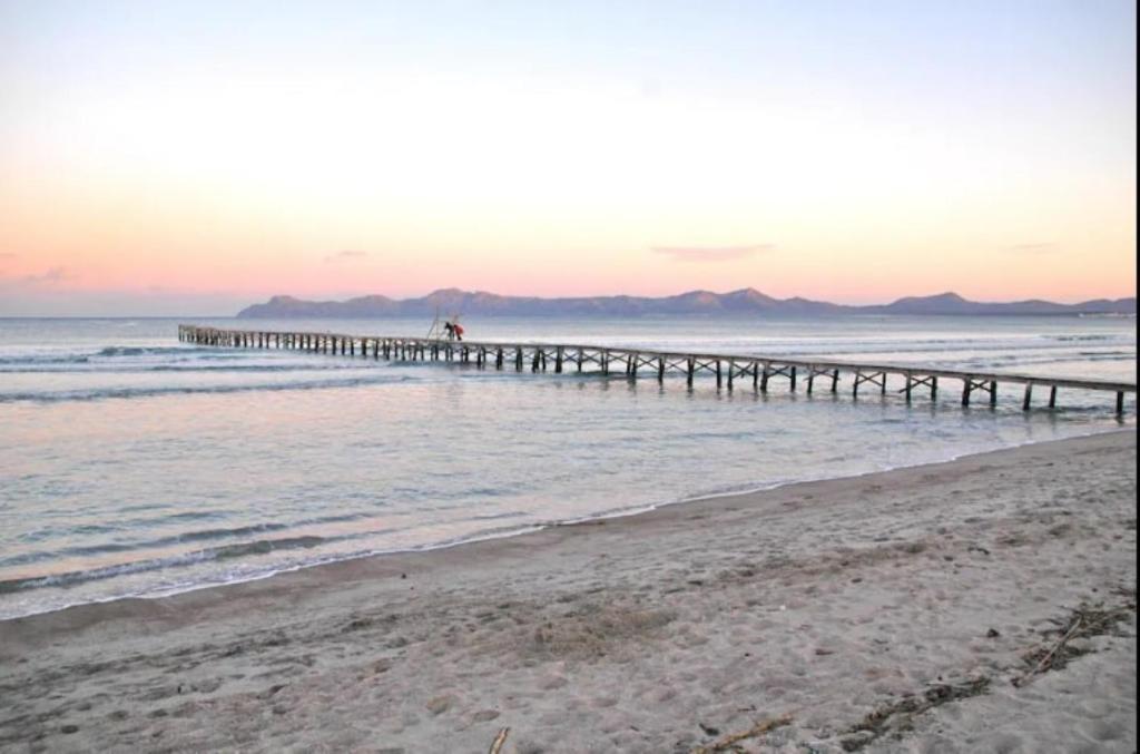 a beach with a pier in the water at Lagomar in Alcudia
