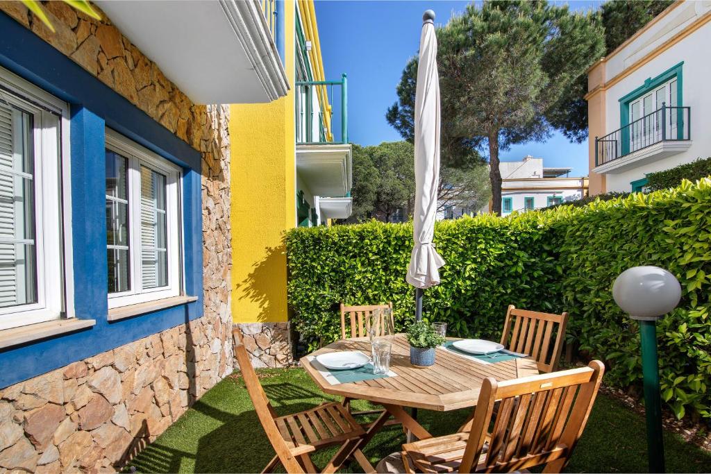 a patio with a table and chairs and an umbrella at Glamorous Villa T3 Praia Verde in Castro Marim