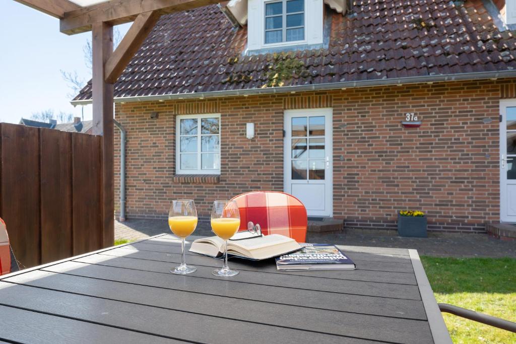a table with two glasses of wine and a book at Haus Möwe und Robbe in Dagebüll