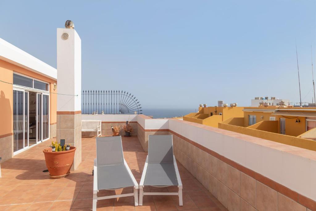 a balcony with two white chairs on a building at Ático San Miguel vacacional in Gáldar