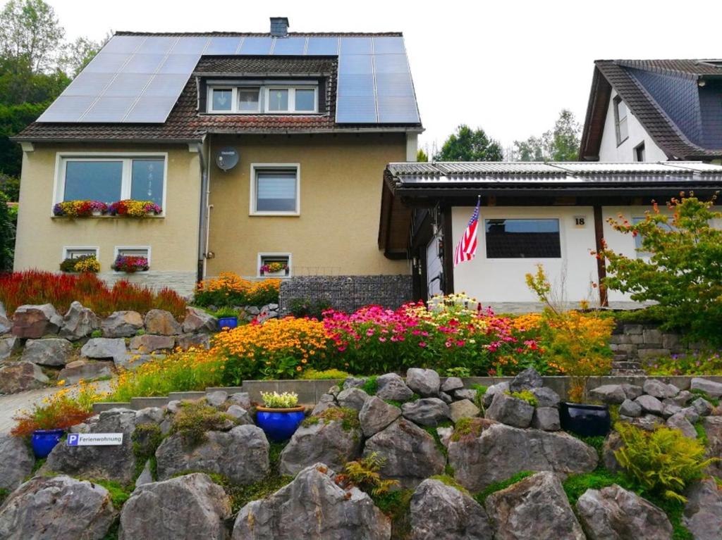 a house with a solar roof and a garden with flowers at Ferienwohnung am Silberg in Plettenberg
