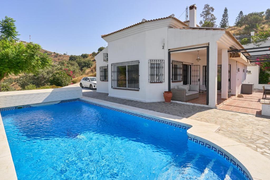 a villa with a swimming pool in front of a house at Villa Amapola in Caserío Carraspite