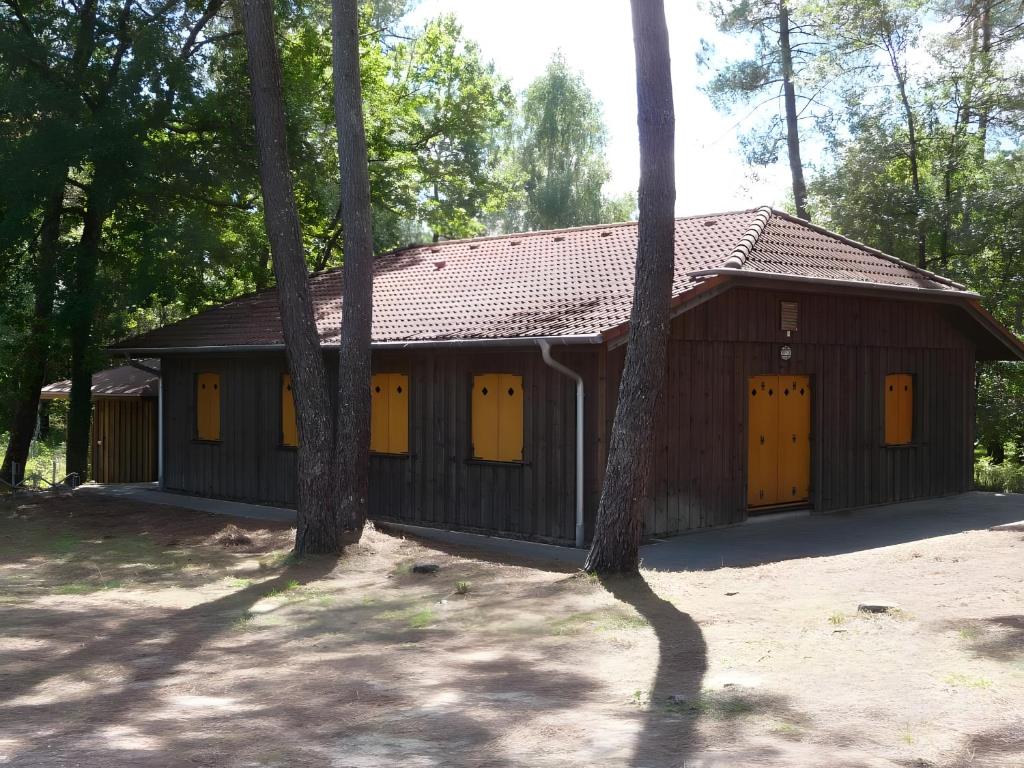 a brown building with yellow doors and trees at Maison Sulz in Montendre